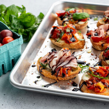 Nordic Ware aluminum quarter sheet pan with golden-brown bruschetta topped with diced tomatoes and herbs