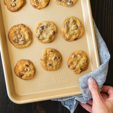 Golden baked chocolate chip cookies arranged on Nordic Ware natural aluminum quarter sheet pan with nonstick surface