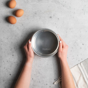 hands grabbing nordic ware 6in layer cake pan