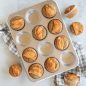 baked cinnamon muffins with apple slice garnish on muffin pan