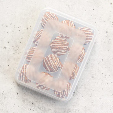 Nordic Ware aluminum muffin pan with clear high-domed lid covering 12 golden baked muffins