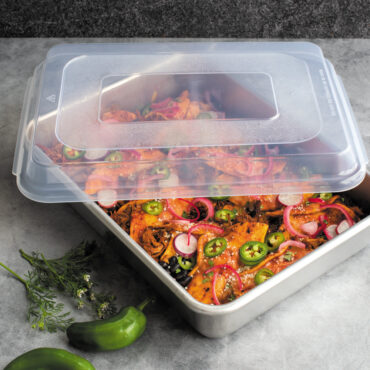 nordic ware 9x13 rectangular cake pan with lid filled with enchiladas