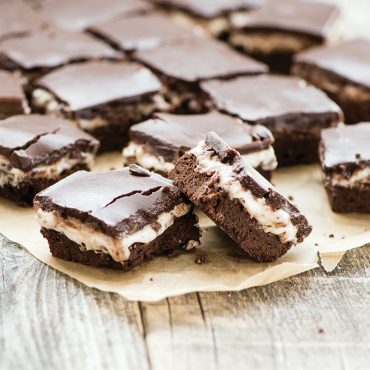 chocolate layer bars with vanilla filling and chocolate frosting on parchment paper