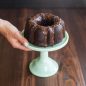 Hand holding cake plate with one chocolate Bundt