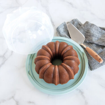 Nordic Ware translucent dome cake keeper cover with sea glass base; cake sever next to golden bundt