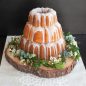 3 tiered baked cakes with glaze, flowers around base of cake, on wood base