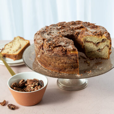 Golden tube cake with one slice cut, baked in Nordic Ware aluminum tube pan showing tall round shape