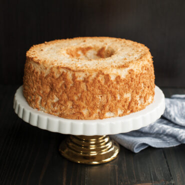 Golden angel food cake on white pedestal cake stand