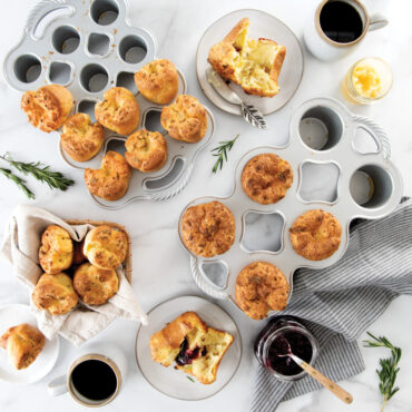 Two Nordic Ware popover pans in different sizes with golden-brown baked popovers, aluminum finish