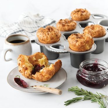 Baked popovers in pan, one plated with jam and coffee on side
