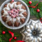 Baked chocolate Vintage Star Bundt cake on plate with white glaze and sugared cranberries in center  with pan