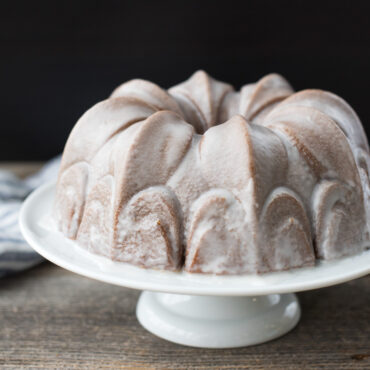 Golden bundt cake with white glaze baked in Nordic Ware Fleur-de-Lis pan, showing fluted petal design