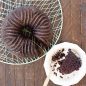 Baked chocolate Bavaria Bundt cake on cooling rack, slice cut out of cake on plate
