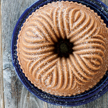 Golden bundt cake with powdered sugar dusting baked in Nordic Ware Bavaria bundt pan, showing ornate fluted pattern