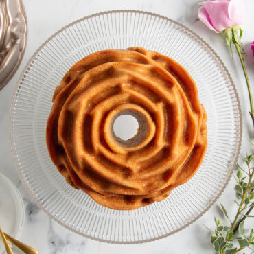 Plain Rose Bundt cake on clear cake stand; overhead