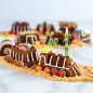 Baked train cake decorated in assortment of candies, formed in a train line on a brown sugar track.