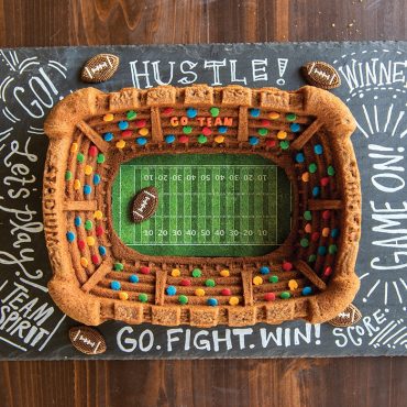 Football theme Stadium Bundt cake, candy footballs, sprinkles as fans, and football themed surface.