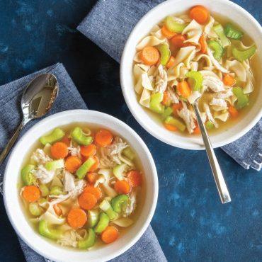 Chicken noodle soup with vegetables in bowls