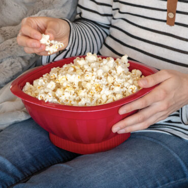 Person holding Nordic Ware red Pro Pop microwave popcorn popper filled with fresh white popcorn