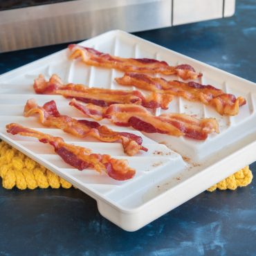 Microwave cooked bacon on tray next to microwave