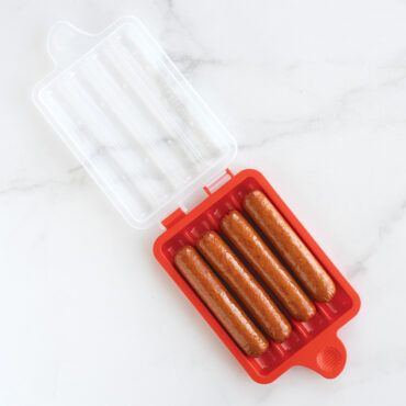 Nordic Ware aluminum hot dog steamer with lid, containing cooked hot dogs in steaming insert