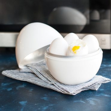 Soft boiled eggs in boiler, one egg cracked open to show soft center