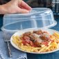 Microwave cover being removed from plate of pasta, meatballs and sauce