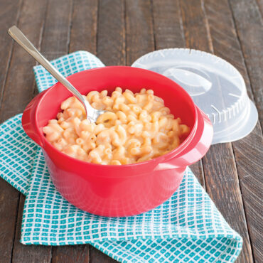 Nordic Ware gray plastic multi boiler with prepared macaroni and cheese, spoon inserted, matching lid beside
