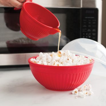 Micro Mix & Melt Bowl pouring melted butter in a bowl of popped popcorn.
