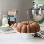 Baked Vanilla Bean Anniversary BundtÂ® cake on stand with ingredients and mixer in background