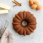 Baked Cinnamon Bundt Cake Mix in Anniversary Bundt Pan with ingredients around cake.