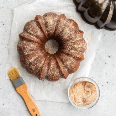 Golden brown cinnamon bundt cake dusted with cinnamon sugar, showing detailed fluted ridges and center hole
