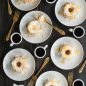 baked angel food cakes on plates with glaze and lemon zest garnish, forks and coffee in cups
