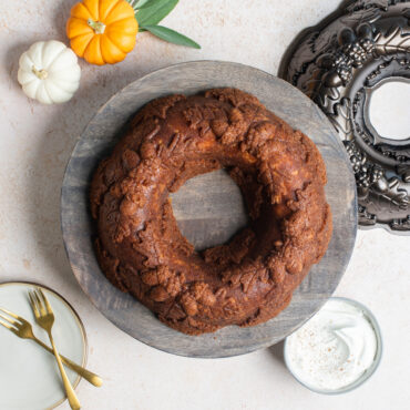 Autumn Wreath Bundt on wooden cake stand with pan and mini pumpkins, overhead