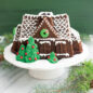Decorated Gingerbread House Bundt cake on a platter with festive greenery