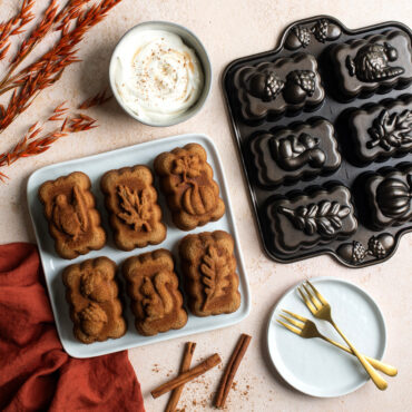 Harvest Mini Loaf Cakes on plate next to pan with dish of whipped cream and cinnamon sticks in scene