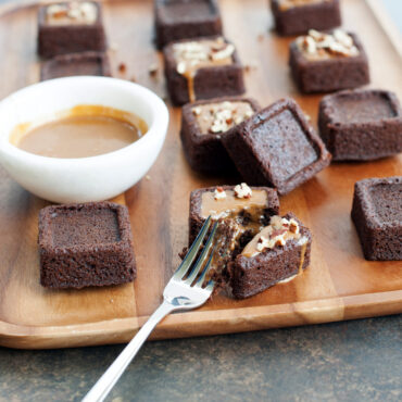 Nordic Ware brownie bites pan with baked square brownies, some topped with caramel and chopped nuts