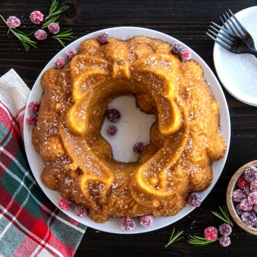 Baked wreath Bundt cake dusted with powdered sugar, fresh cranberries for garnish