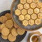 Baked honeycomb cake with bee cookie stamps on plate with honey jar with dipper on surface