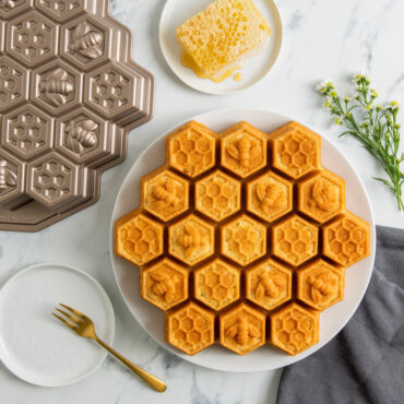Golden honeycomb pull-apart cake and pan with small plate of honey comb drizzled with honey