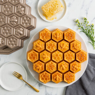 Golden honeycomb pull-apart cake covered with honey and pan with small plate of honey comb drizzled with honey