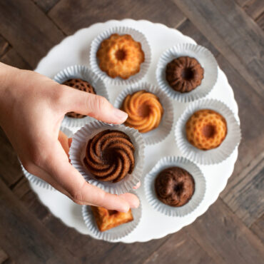 Hand selecting golden mini bundt cake from Nordic Ware aluminum Bundt Charms pan with 8 fluted cavities