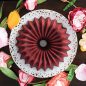 Baked red velvet cake on serving plate, fresh flowers around serving plate