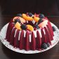 Red velvet Brilliance Bundt pan with blackberries, peaches, pomegranate seeds and white glaze