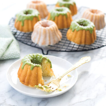 Nordic Ware Anniversary Bundtlette pan with baked mini bundt cake, aluminum with intricate fluted design