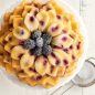 Overhead Baked Blossom Bundt Cake with blackberries in the center, dusted with powdered sugar.