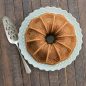 Baked vanilla Vaulted Cathedral Bundt cake on plate, overhead with serving tool