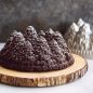 Close up Chocolate Gingerbread Pine Forest Bundt Cake on wooden plate, pan in background, dusted with powdered sugar