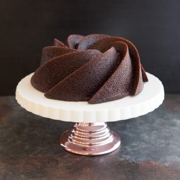 Baked chocolate cake on cake stand, angled view