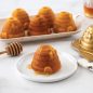 Baked almond beehive cakelets on platter, one plated with drizzled honey